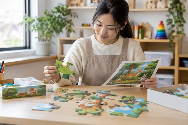 Asian adult early-learning educator examining puzzle pieces and a reference image