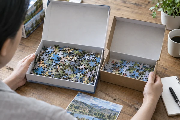 hands of an Asian adult comparing usable storage space in two puzzle boxes