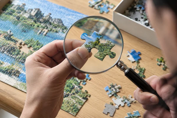 macro of a detailed cardboard puzzle photograph beside a magnifier